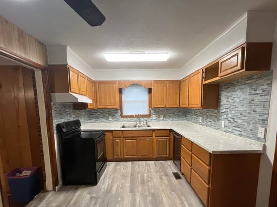 Kitchen with oak cabinets, a tile backsplash and grey plank flooring